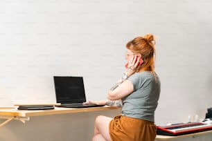 uma mulher sentada em uma mesa usando um computador portátil