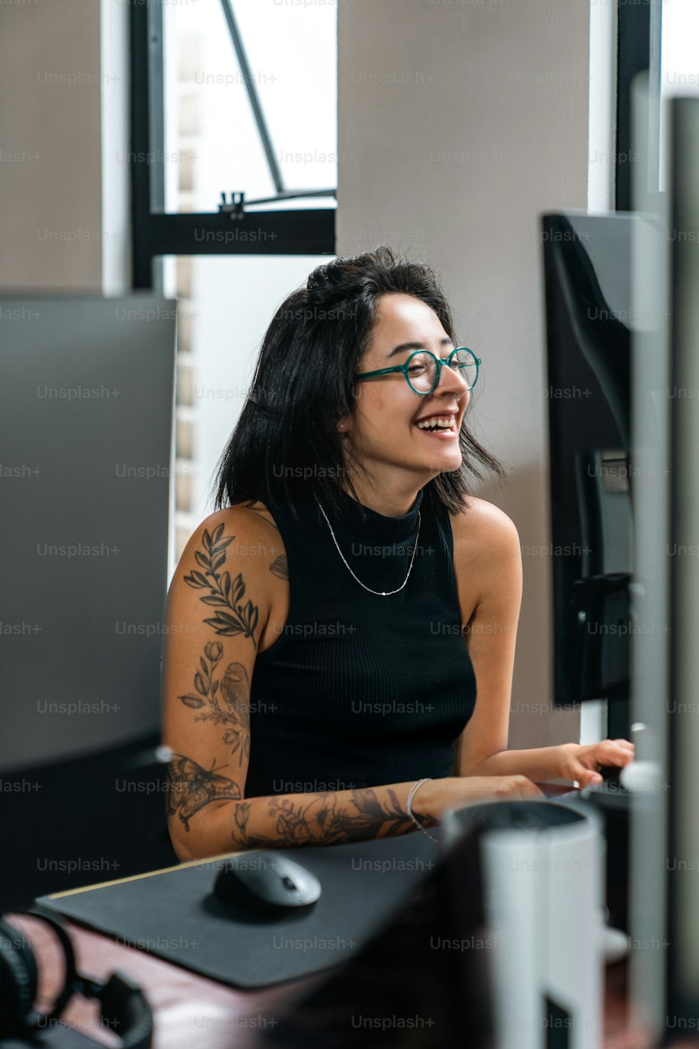 a woman with a tattoo on her arm sitting in front of a computer