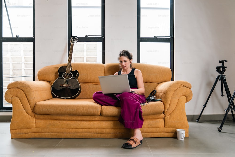 uma mulher sentada em um sofá usando um laptop