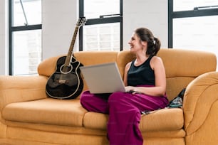 a woman sitting on a couch using a laptop computer