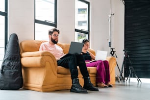 Ein Mann und eine Frau sitzen mit einem Laptop auf einer Couch