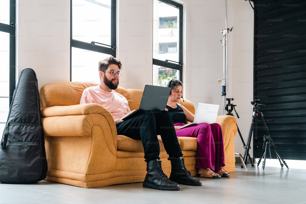 a man and woman sitting on a couch with a laptop