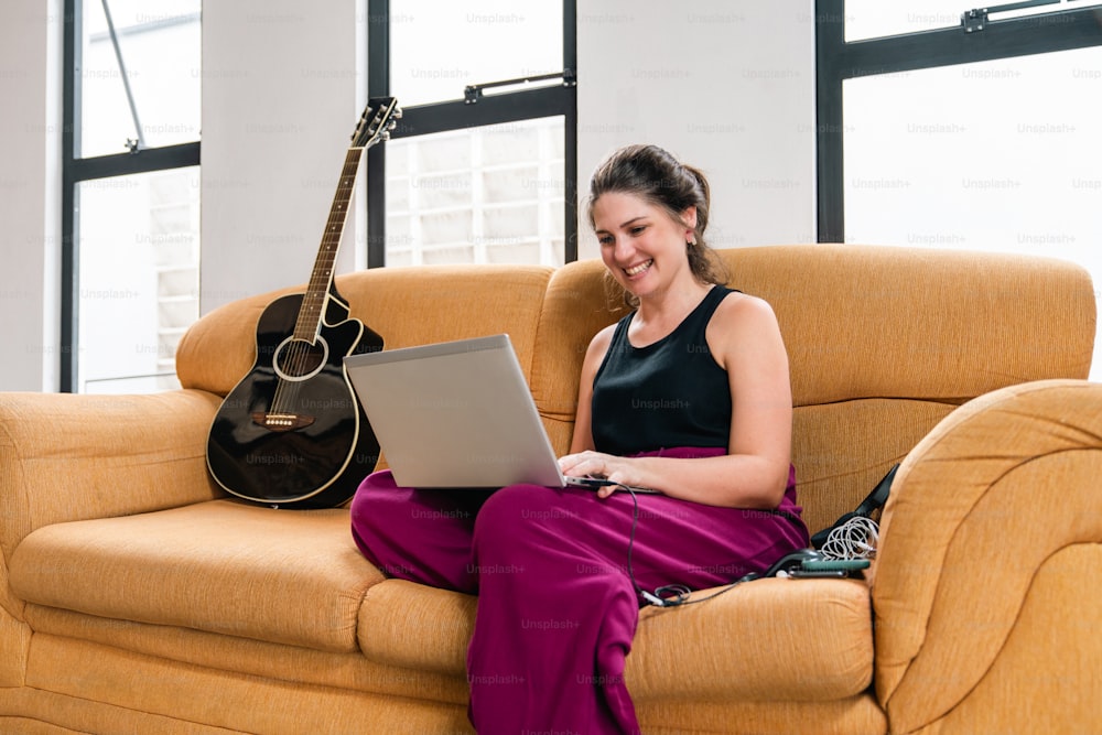 노트북 컴퓨터를 사��용하여 소파에 앉아 있는 여자
