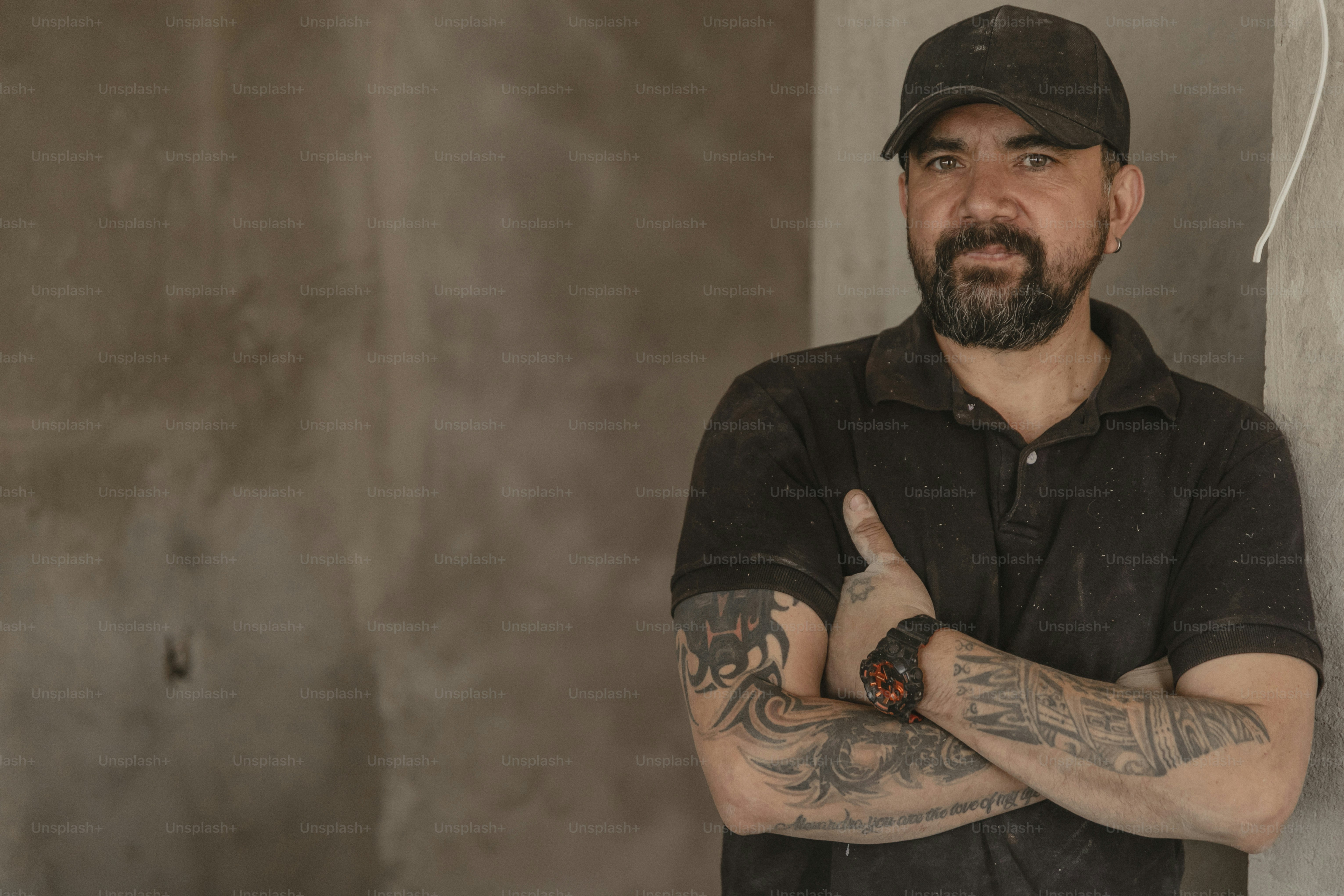 a man with a beard wearing a black shirt and a hat