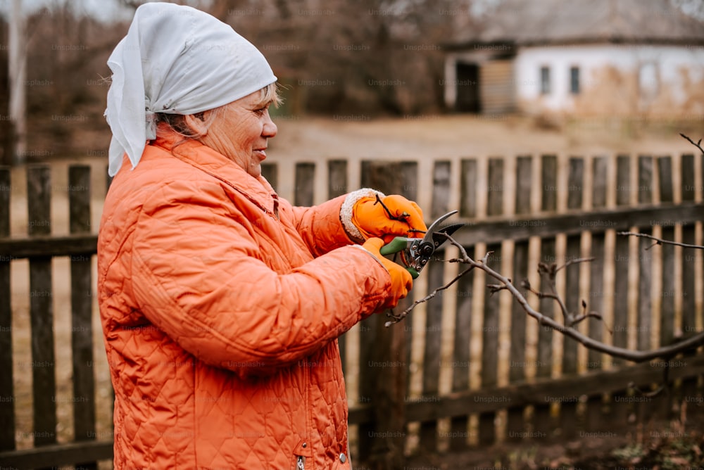 a woman in an orange jacket is holding a branch