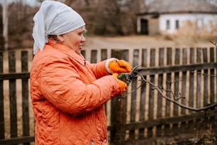 a woman in an orange jacket is holding a branch