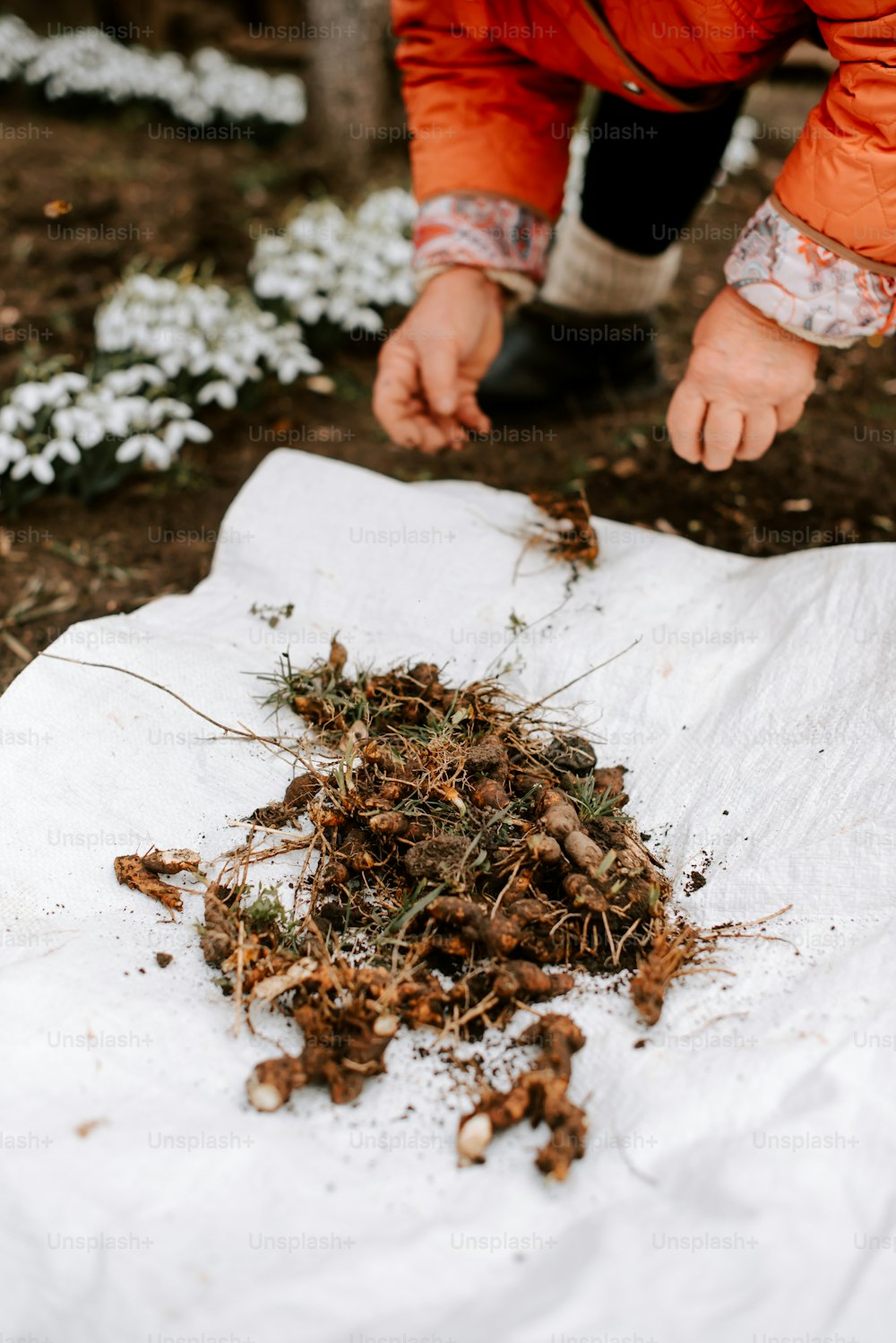 a person in an orange jacket picking up a pile of dirt