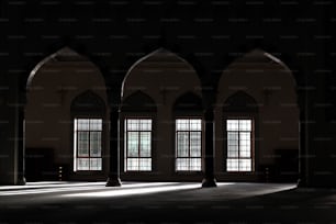 a dimly lit room with three windows and arches