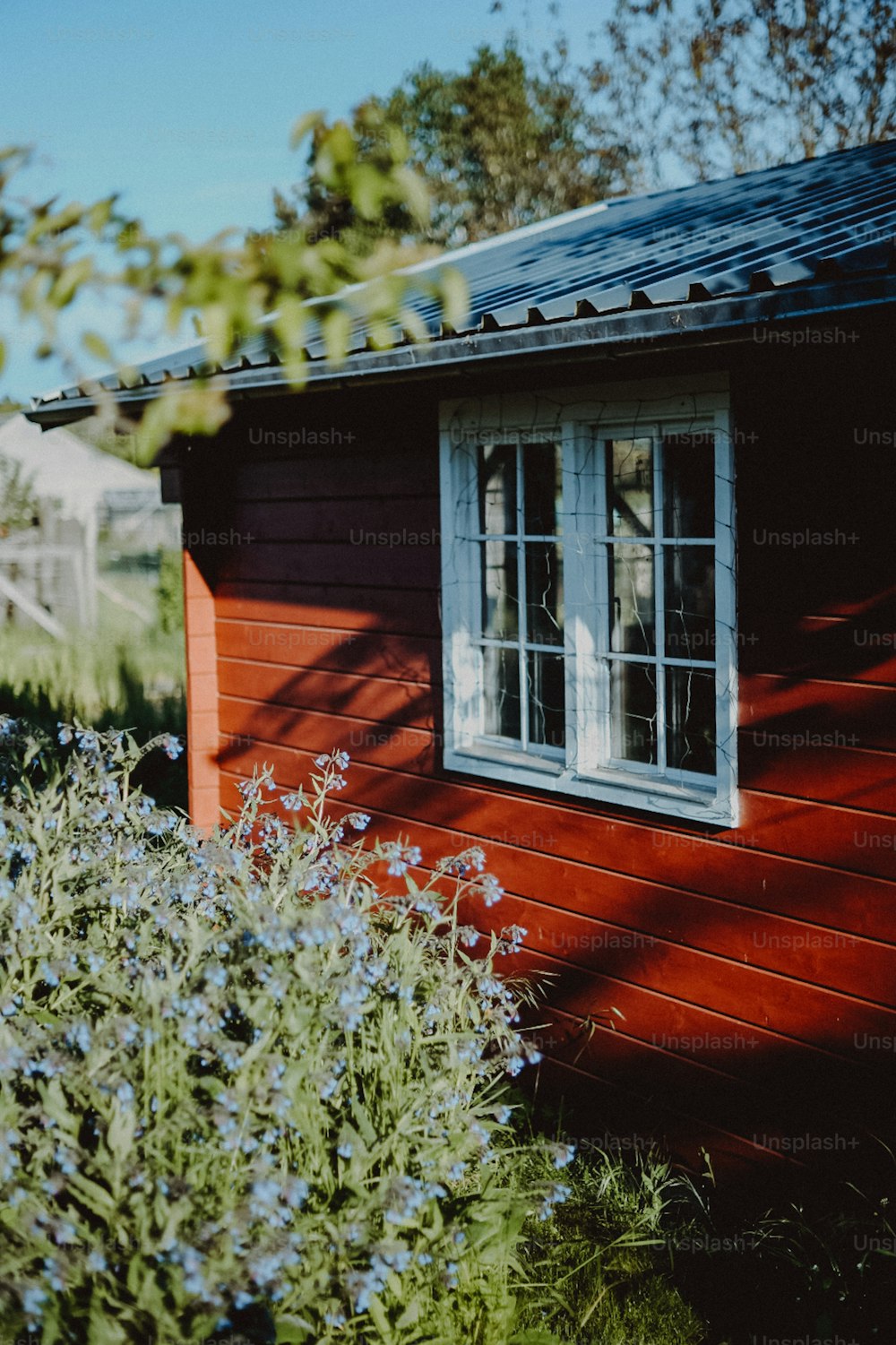 uma pequena casa vermelha com uma janela branca