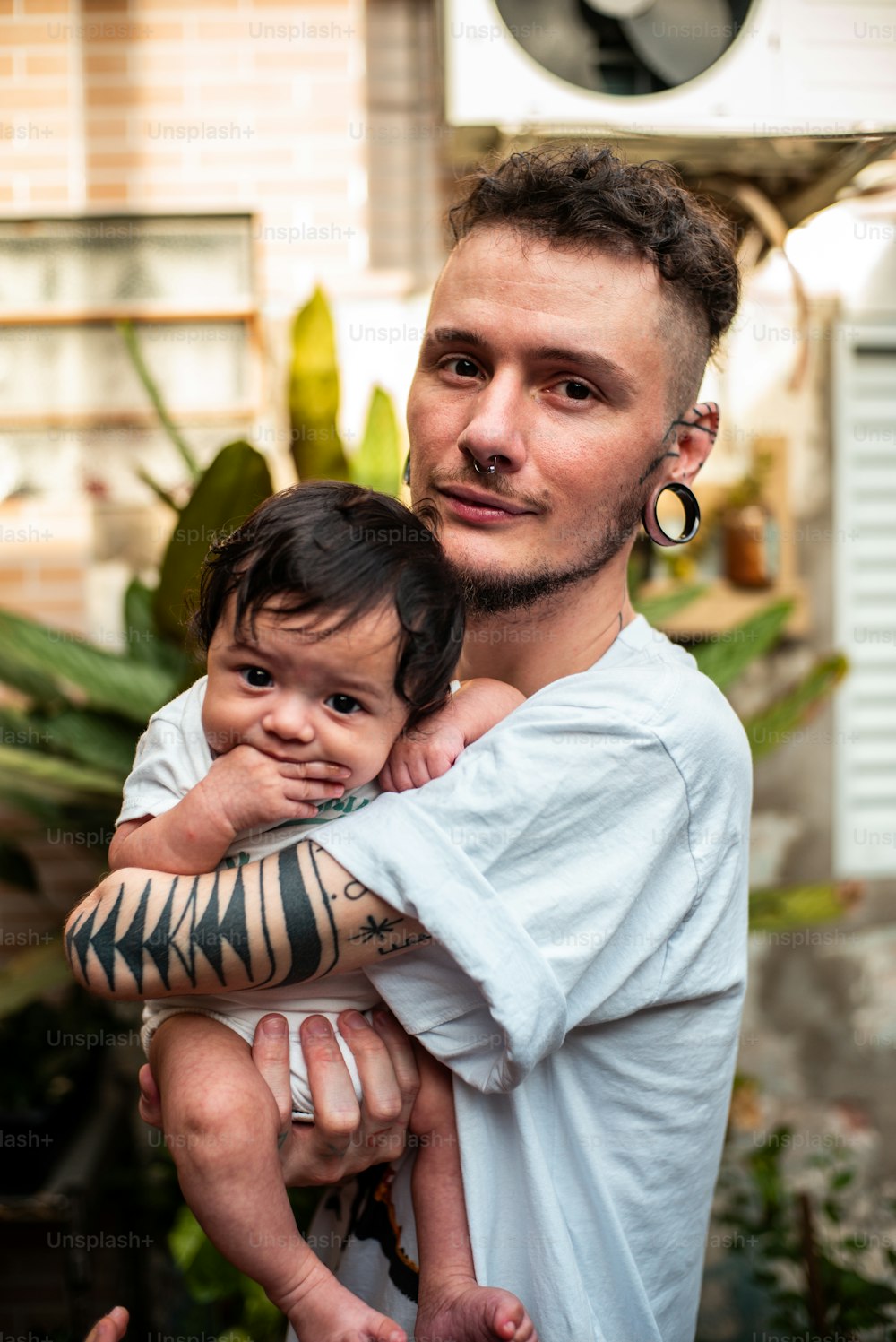 a man holding a baby with a tiger tattoo on his arm