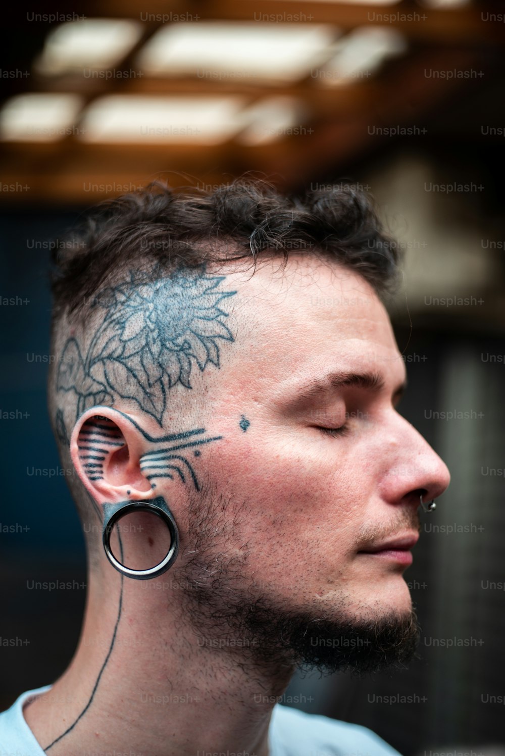 Un uomo con un tatuaggio sul viso e sull'orecchio