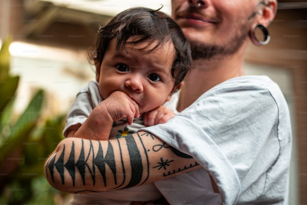 a man holding a baby with a tattoo on his arm