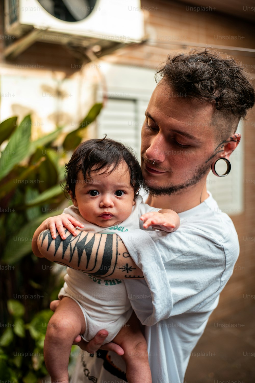 um homem segurando um bebê com uma tatuagem em seu braço