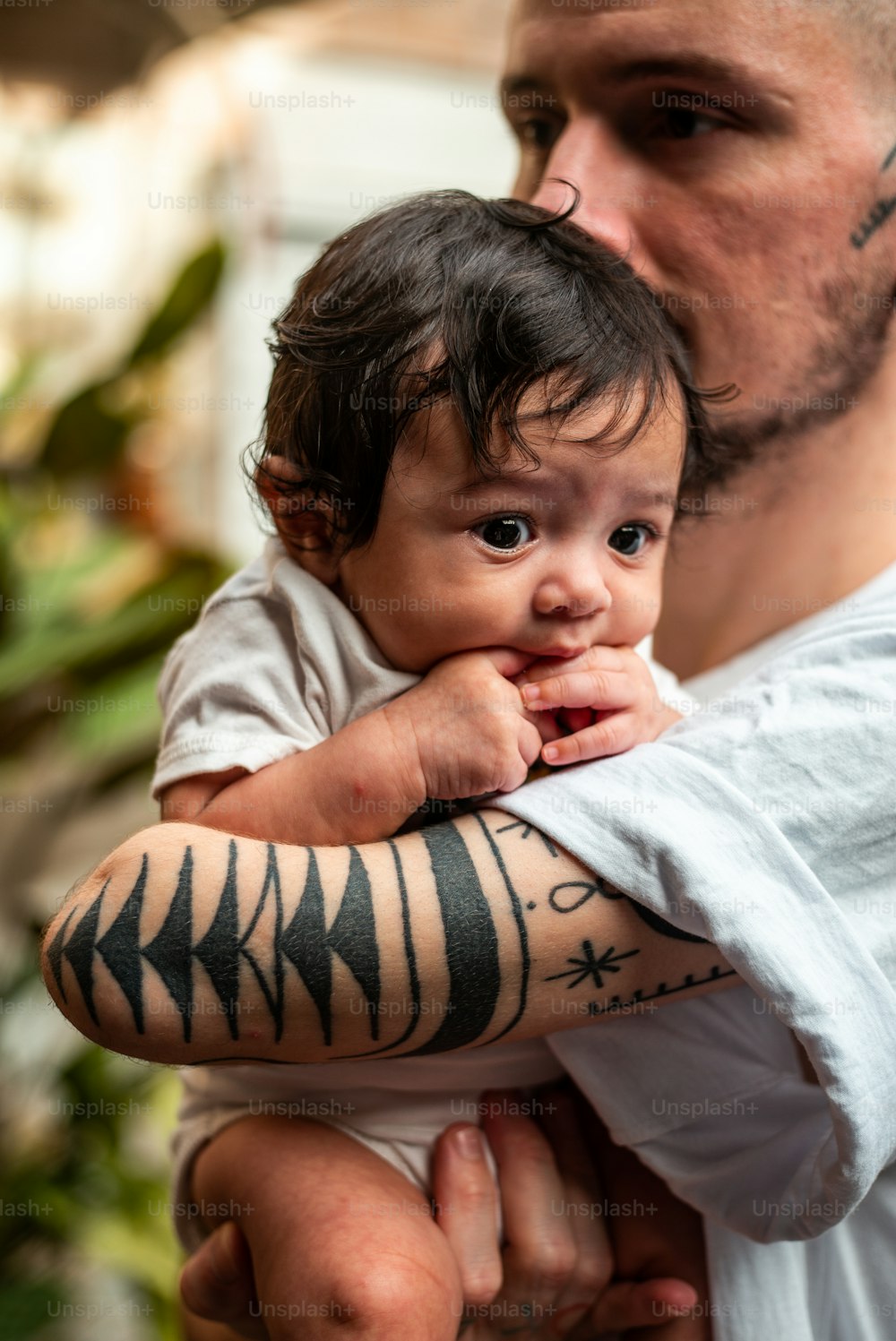 a man holding a baby with a tattoo on his arm