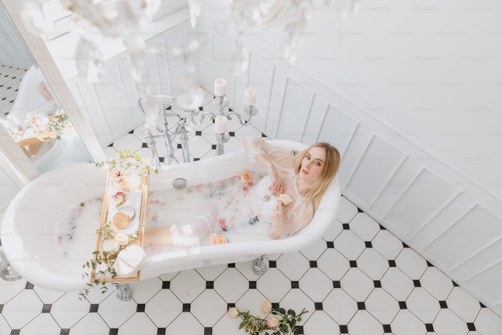 una donna seduta in una vasca da bagno piena di fiori