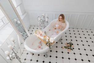 a woman sitting in a bathtub with flowers on the floor