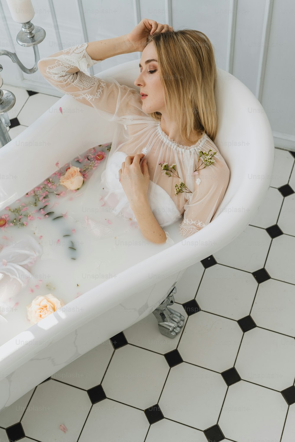 Une femme assise dans une baignoire avec des fleurs partout
