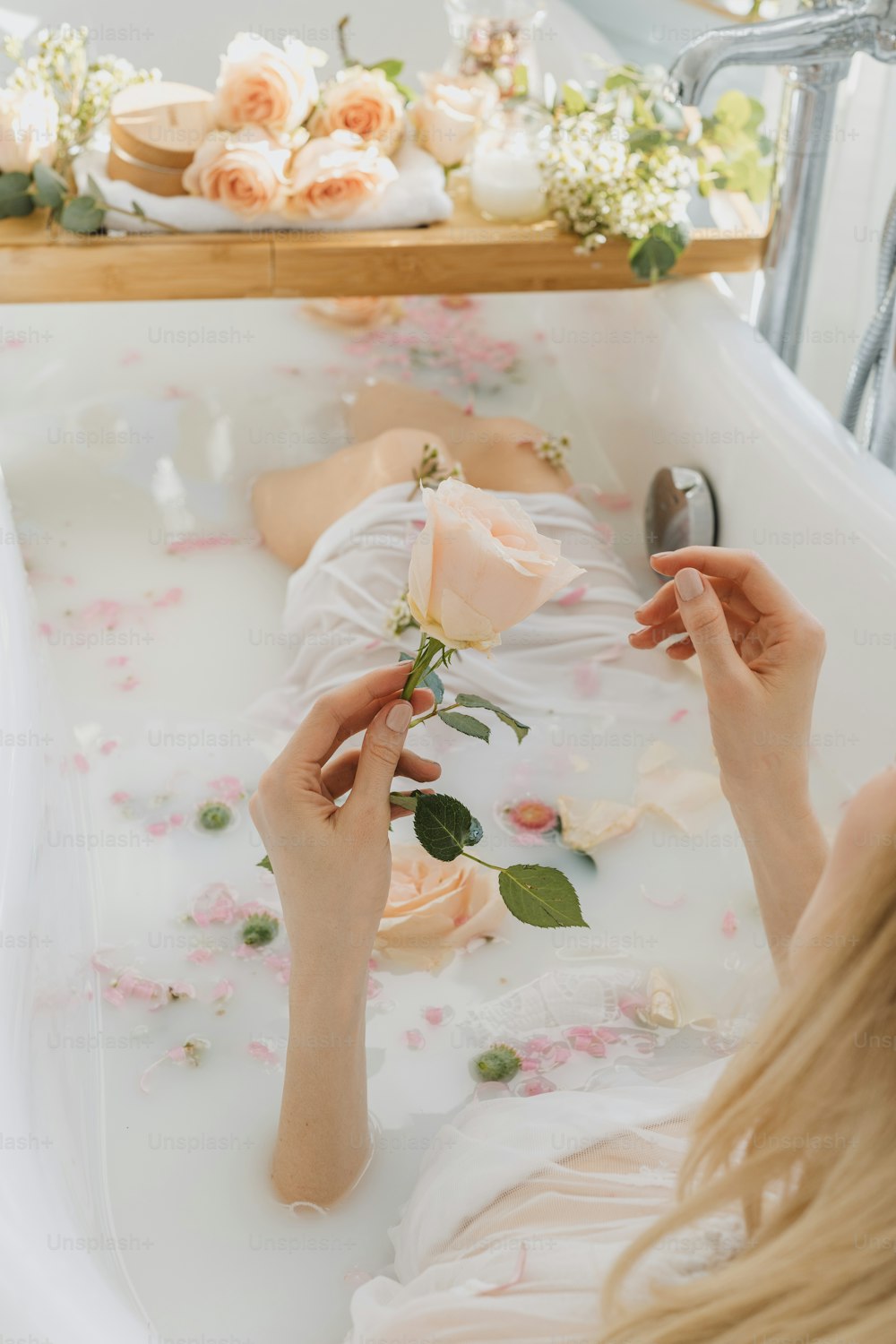 a woman laying in a bathtub with flowers on it