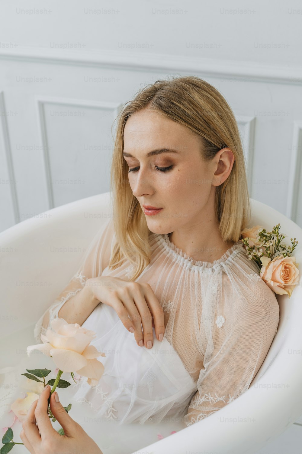 Una mujer sentada en una bañera sosteniendo una flor