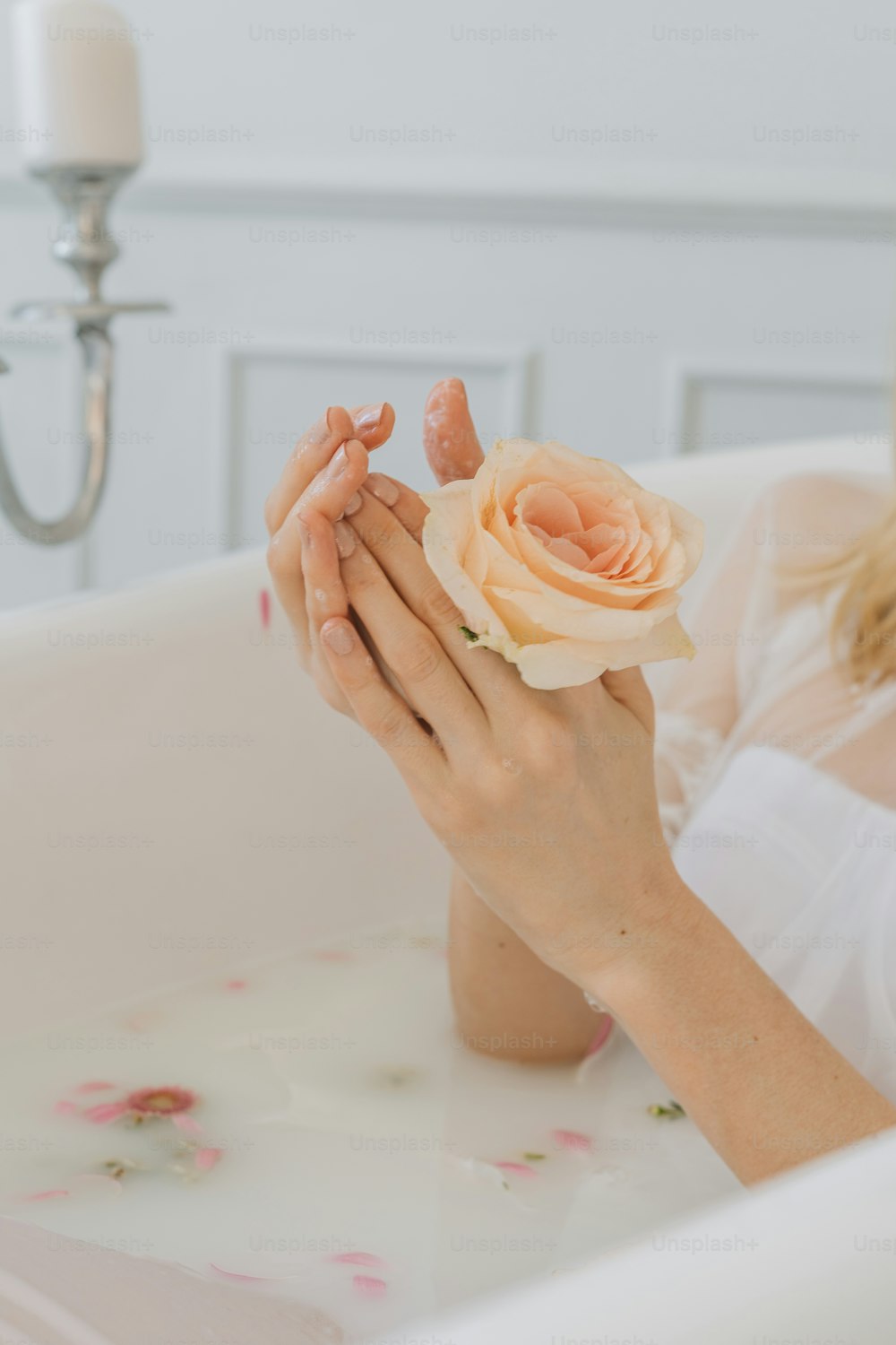 uma mulher sentada em uma banheira segurando uma flor