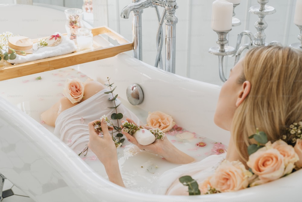 uma mulher sentada em uma banheira com flores sobre ele