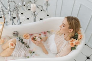 a woman sitting in a bathtub with flowers around her