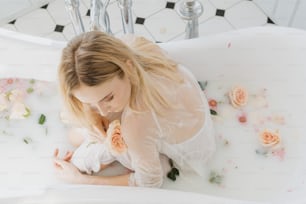 a woman in a bathtub with flowers on the floor