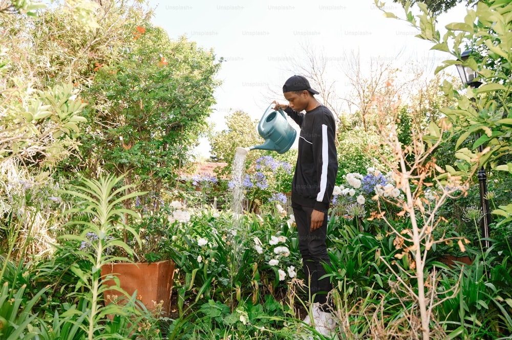 Un hombre regando su jardín con una regadera
