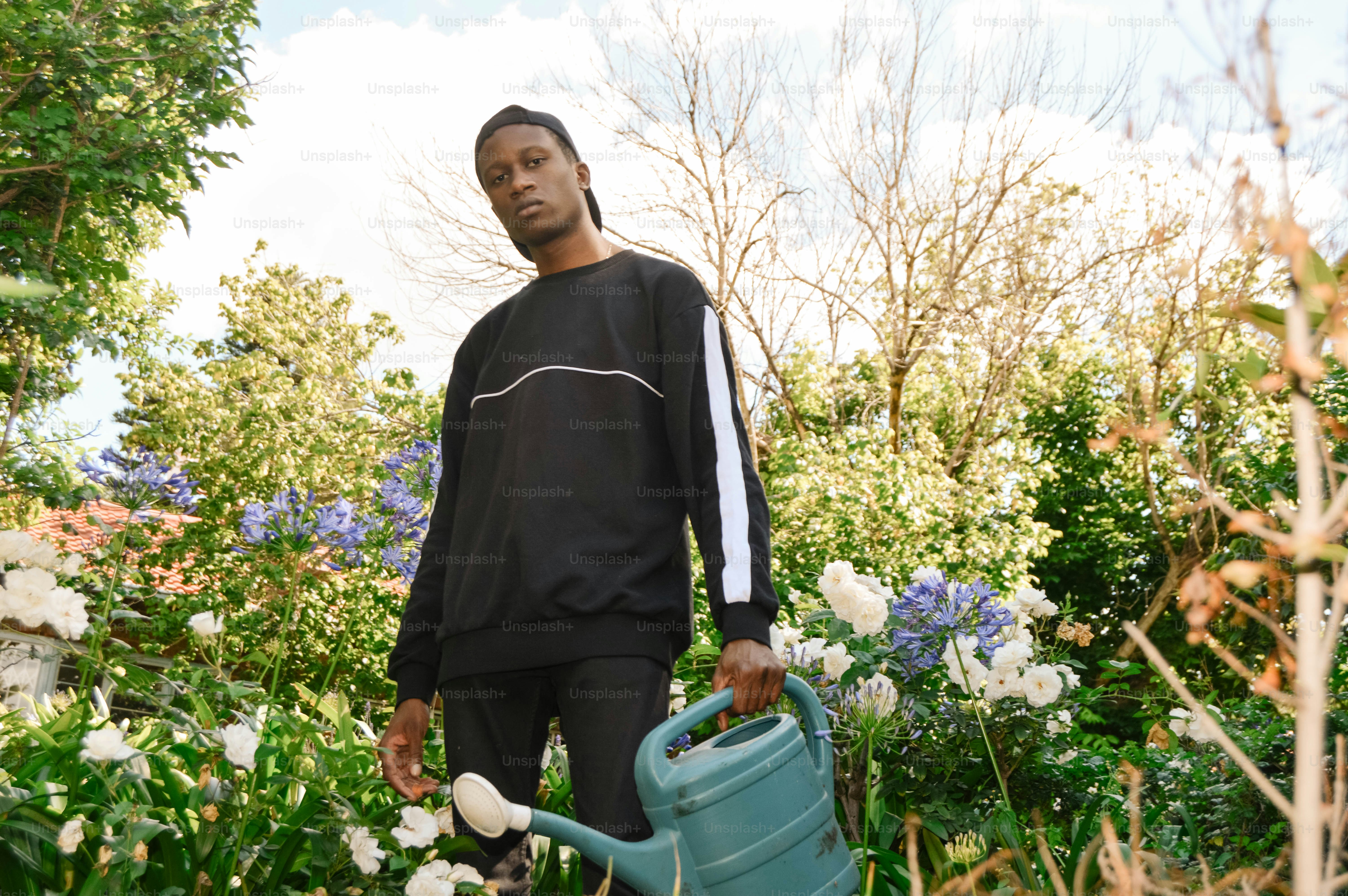 a man holding a watering can in a garden