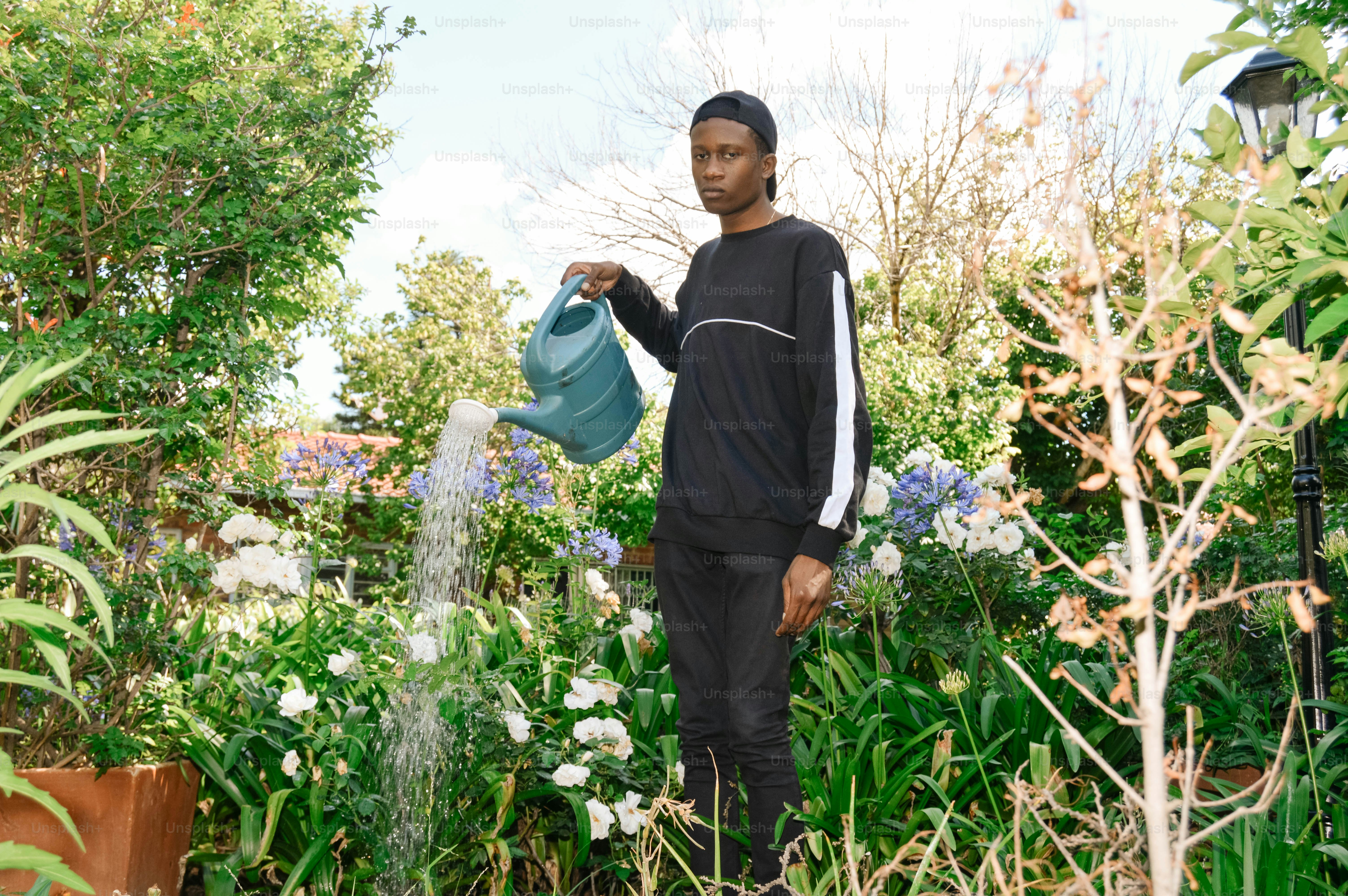 a man holding a watering can in a garden