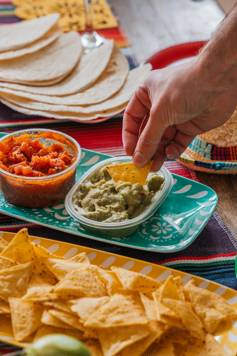 a person dipping a tortilla into a bowl of guacamole