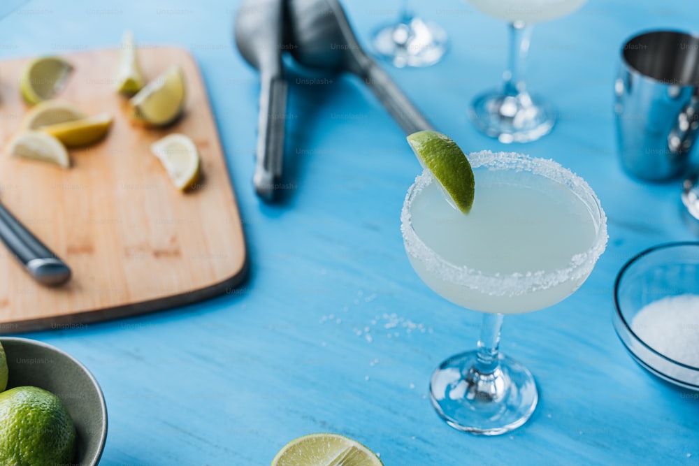 a blue table topped with a margarita and limes