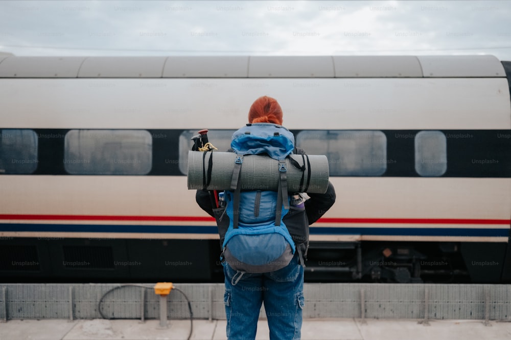 a person with a backpack standing in front of a train