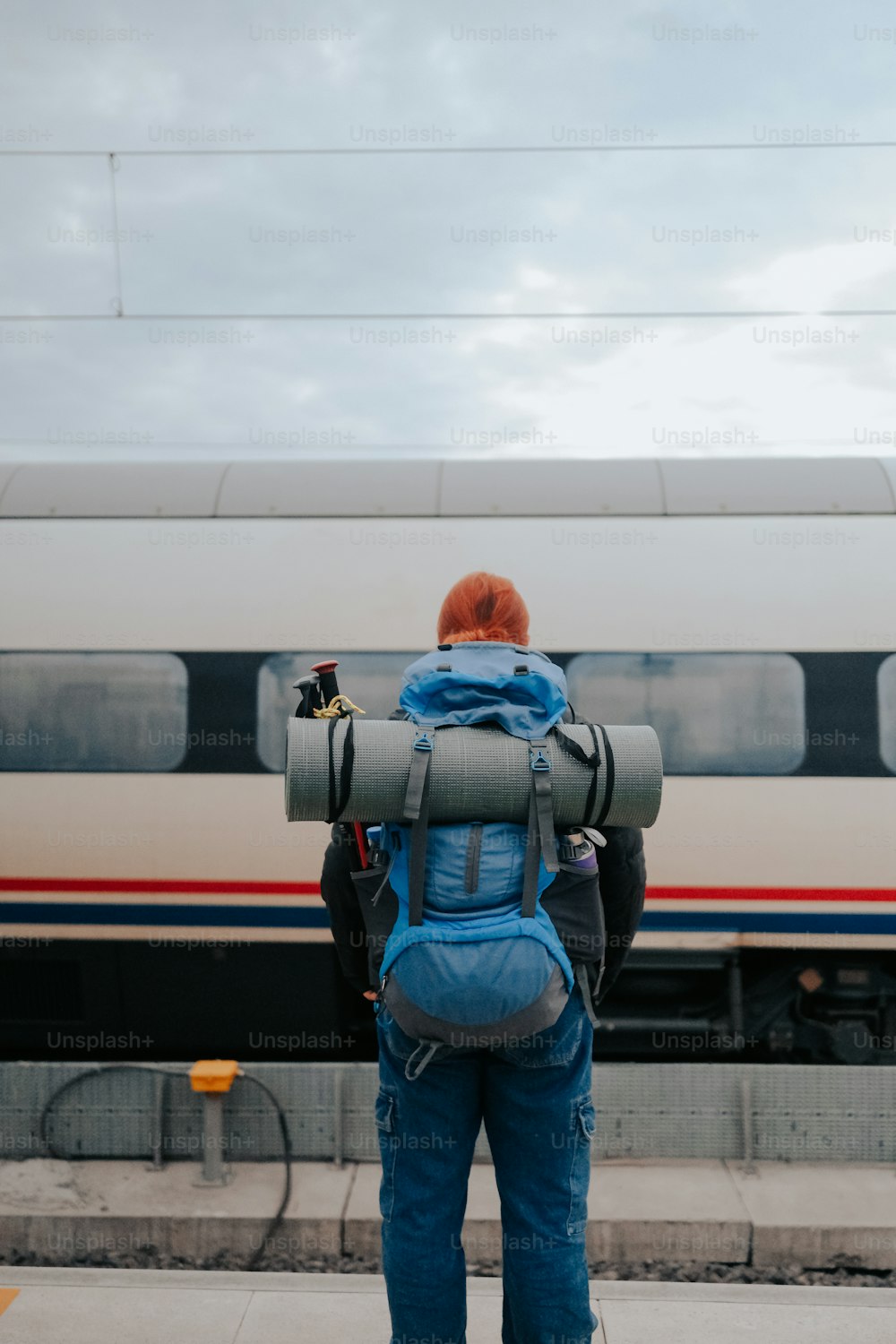a person with a back pack standing in front of a train
