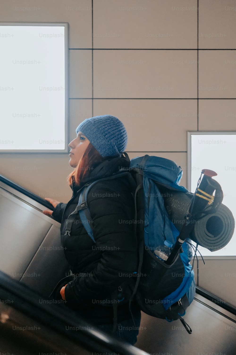 a woman with a backpack riding an escalator