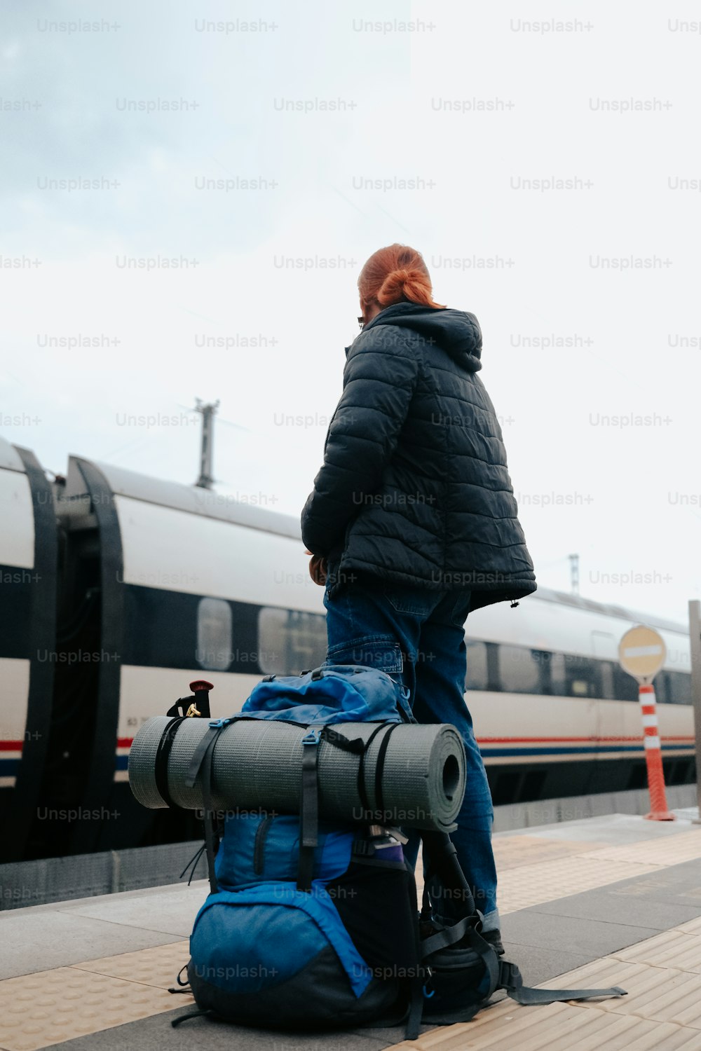 a man standing on a platform with a backpack and a train in the background