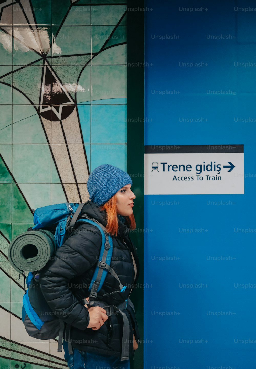 a woman with a blue backpack standing in front of a blue wall