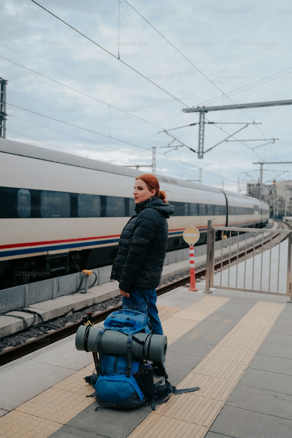 a woman standing next to a train with a backpack on her back