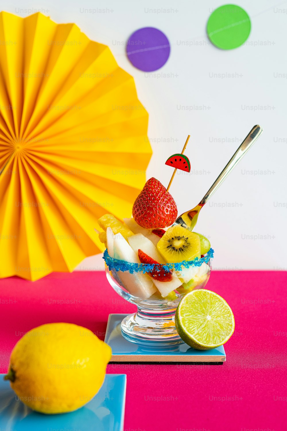 a fruit sundae with a yellow umbrella in the background