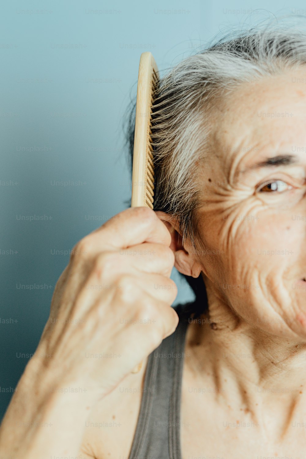 an older woman brushes her hair with a wooden comb