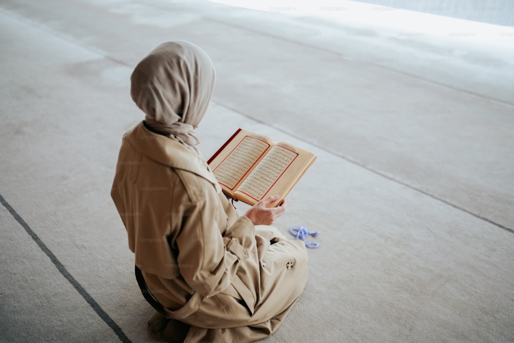 une personne assise par terre en train de lire un livre
