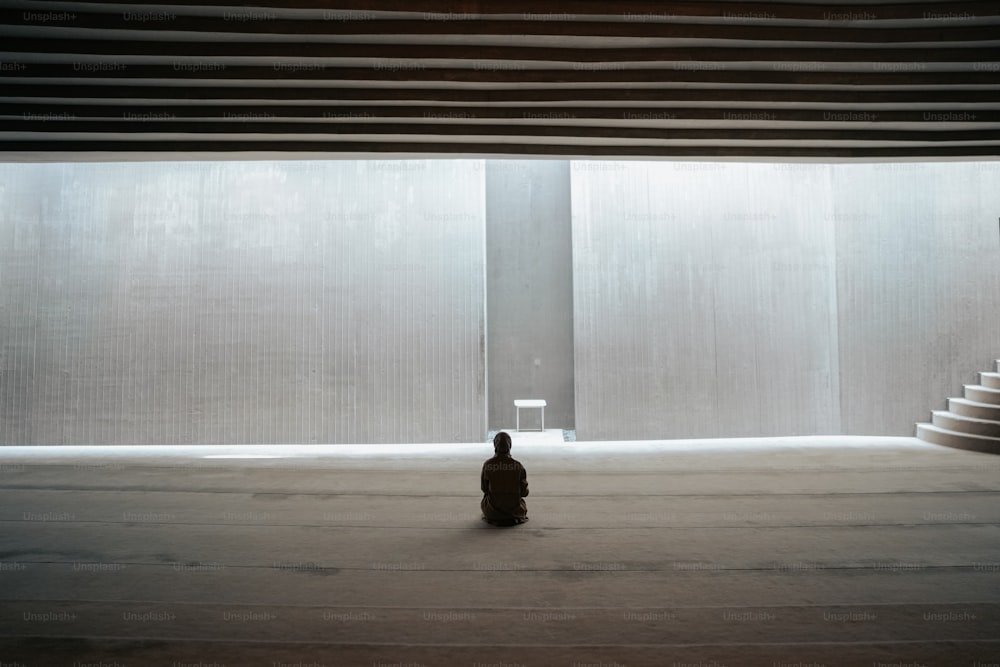 una persona seduta sul pavimento di fronte a una finestra