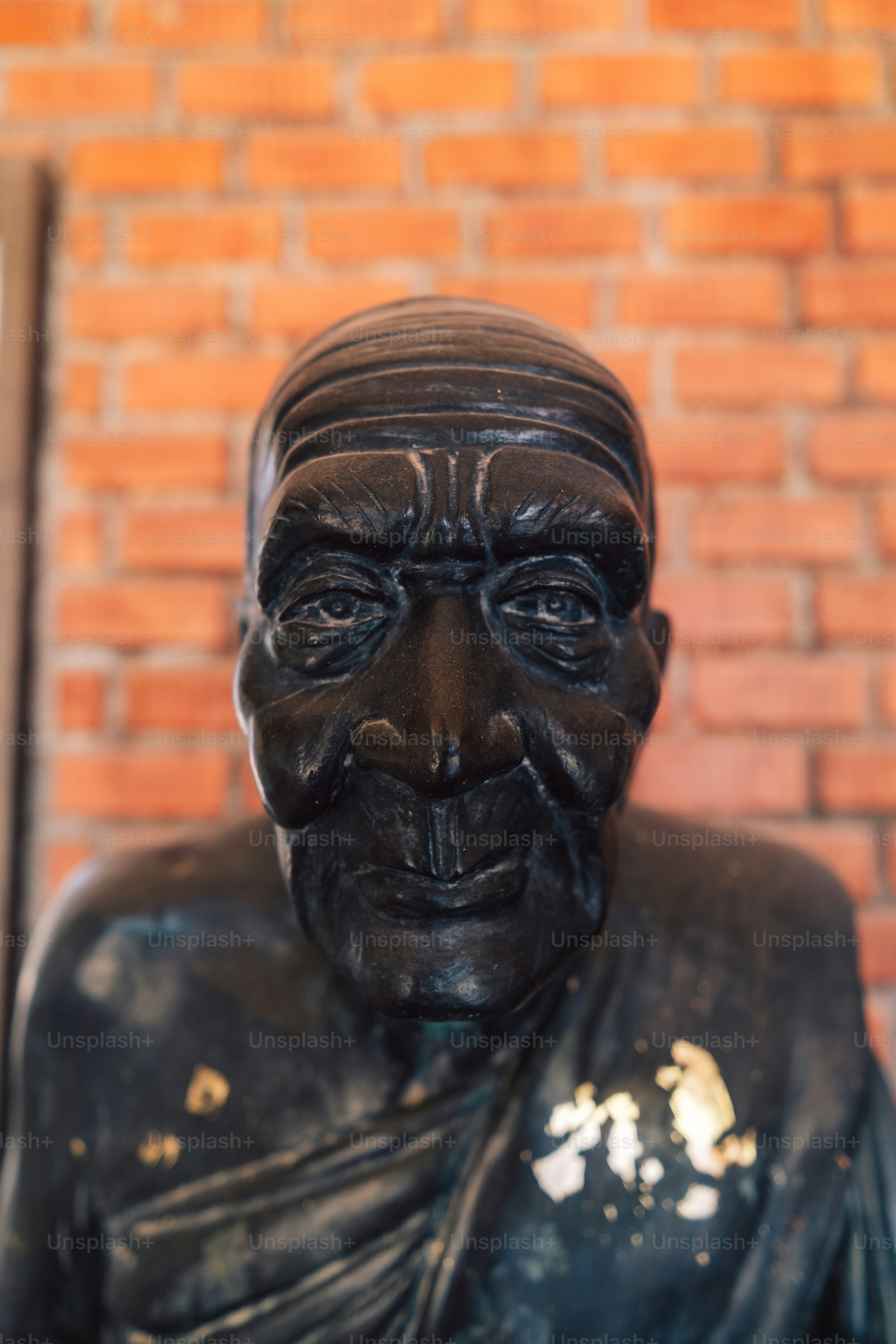 Un primo piano di una statua di un uomo di fronte a un muro di mattoni