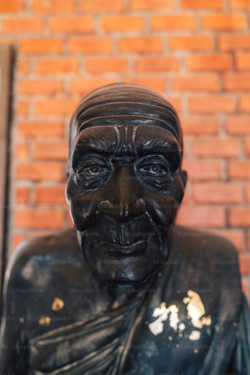 um close up de uma estátua de um homem na frente de uma parede de tijolos