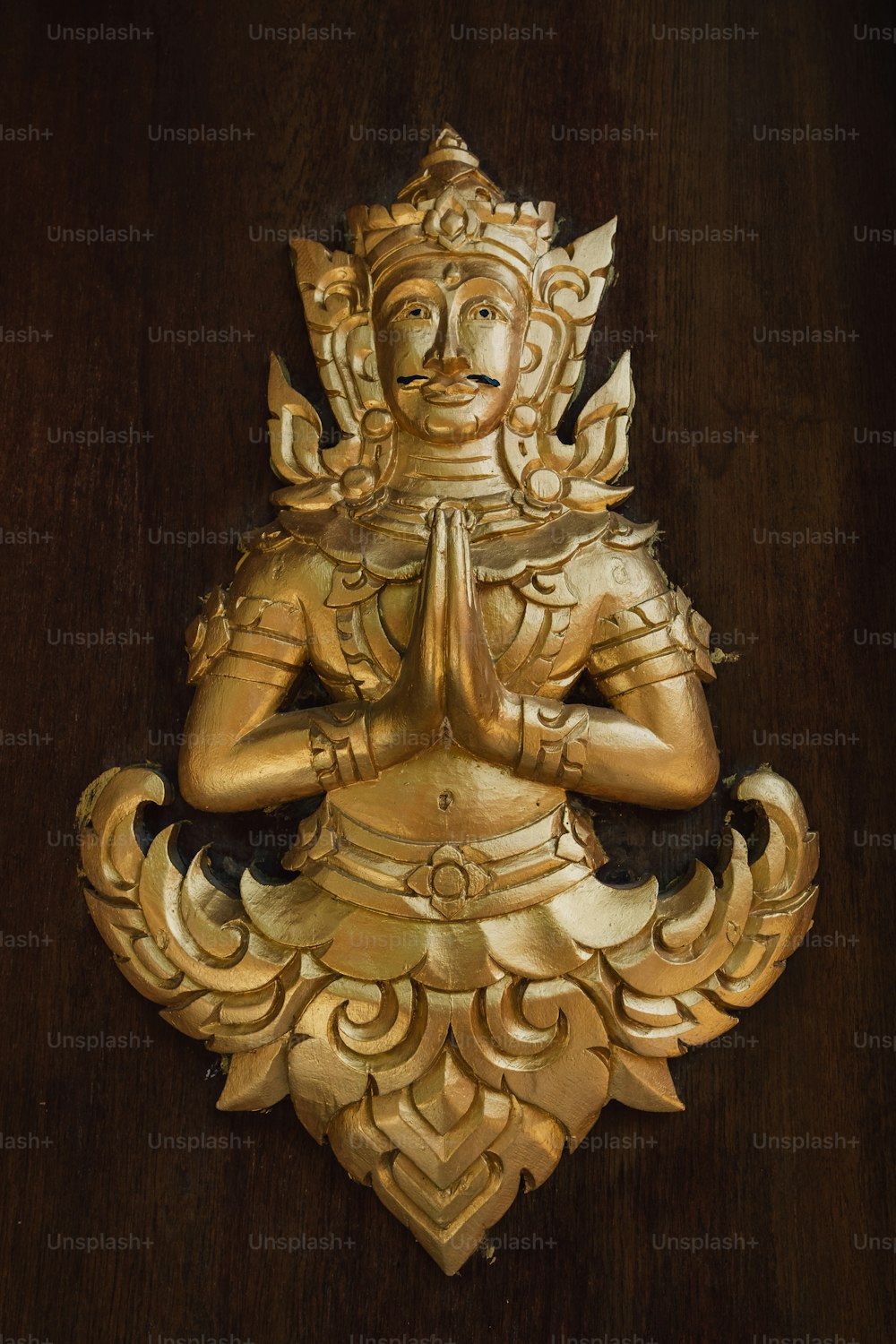uma estátua dourada de uma pessoa sentada em uma posição de lótus