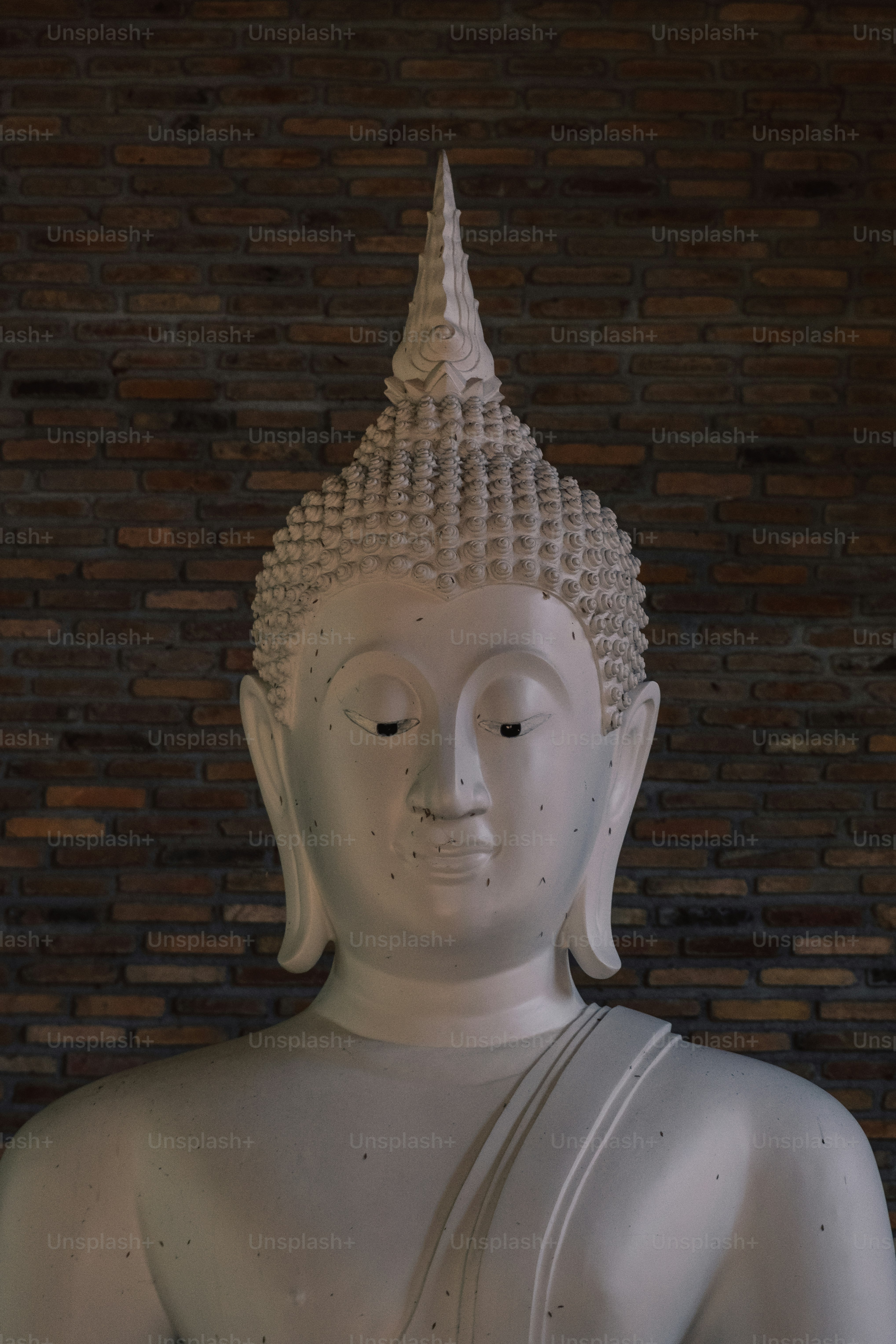 A white buddha statue sitting in front of a brick wall photo Faith