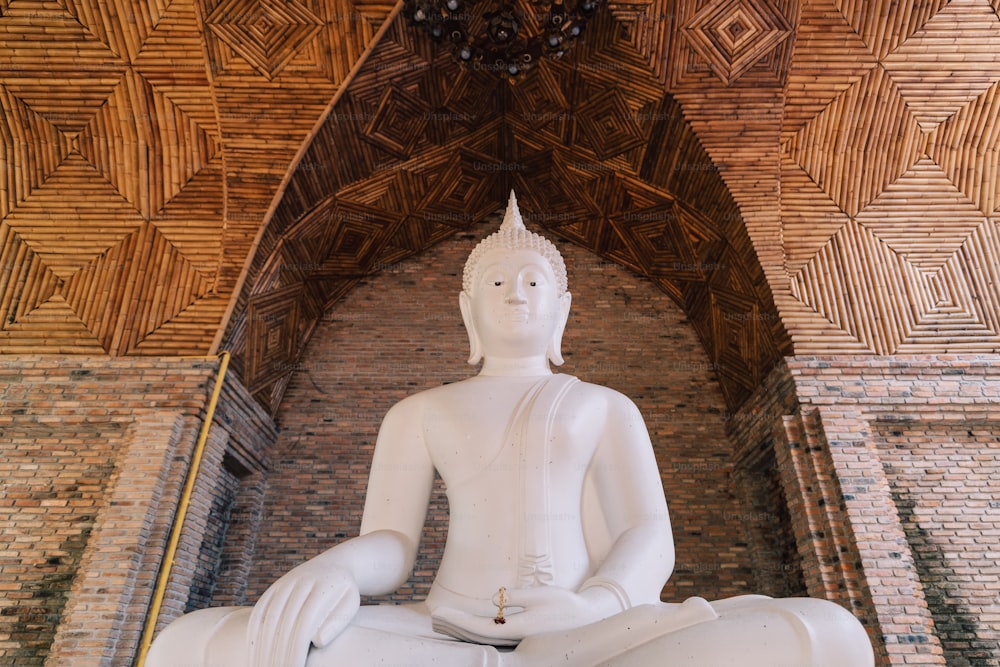 uma estátua branca de Buda sentada no meio de uma sala