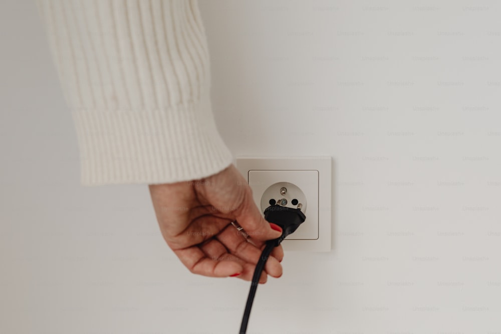 a person is plugging in to a wall outlet
