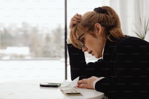 a woman sitting at a table writing on a piece of paper