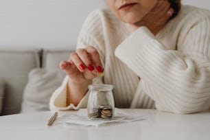 a woman sitting at a table with a jar of coins